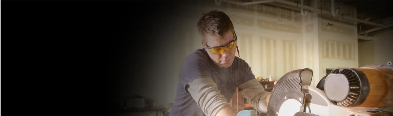 Man wearing protective glasses in workshop and using equipment